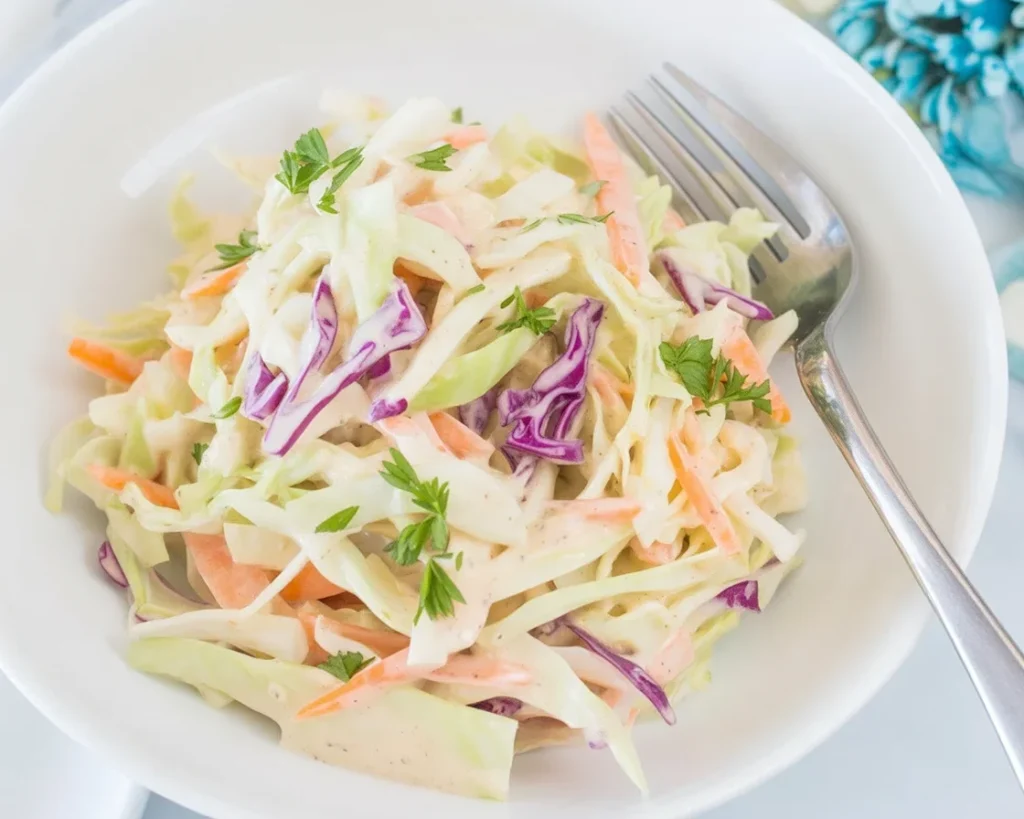 Creamy coleslaw dressing made with mayonnaise, vinegar, and spices in a bowl.